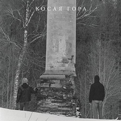 Black and white photo of two figures near a stone column in a forest.