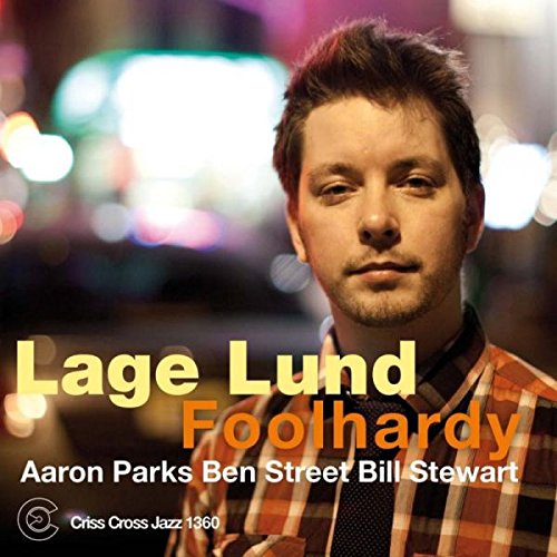 Album cover featuring a man in a plaid shirt against a blurred city lights background.