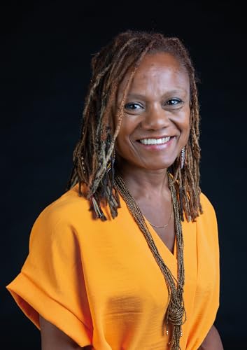Smiling Black woman with dreadlocks wearing an orange top.