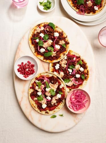 Overhead view of flatbreads with toppings on a marble surface.