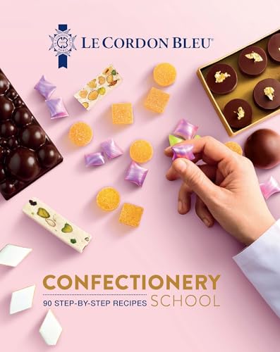 A hand picks up a purple candy among various confections on a pink background.