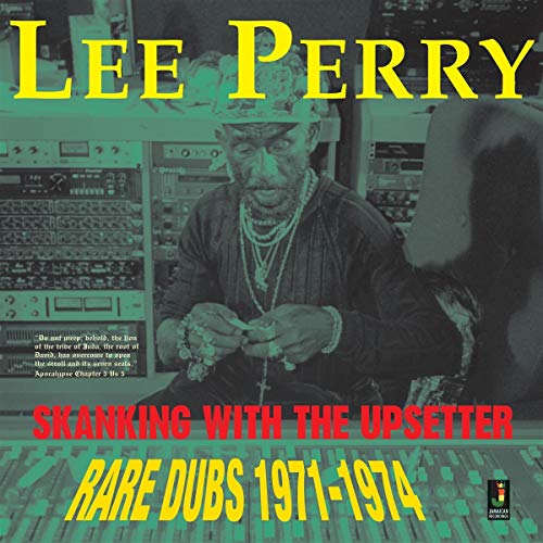 Lee Scratch Perry sitting at a mixing console in a recording studio.