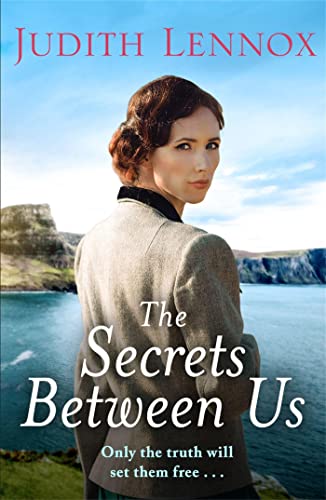 Book cover: woman in grey coat, coastal landscape, title "The Secrets Between Us".