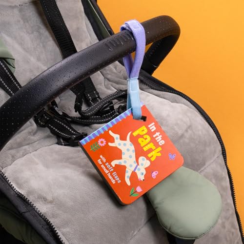Small orange board book, “In the Park,” hanging from a stroller handle.