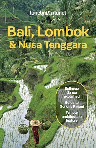 A person with baskets walks through lush green terraced rice paddies in Bali.