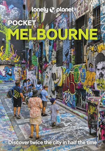 A group of people walks through a narrow alleyway covered in colorful graffiti.