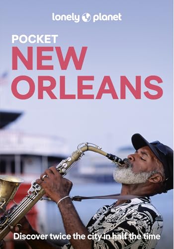 A man with a gray beard plays a saxophone against a blurred waterfront background.