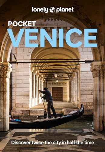 A gondolier rows a boat through a stone archway in Venice, Italy.