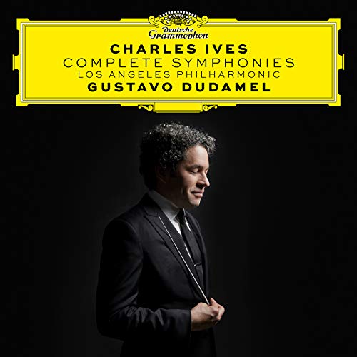 Gustavo Dudamel in a suit holding a baton against a black background.