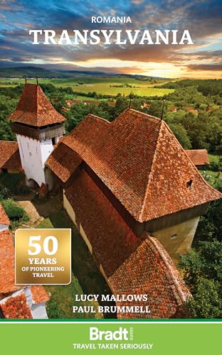 Aerial view of a historic Transylvanian church with red tiled roofs at sunset.
