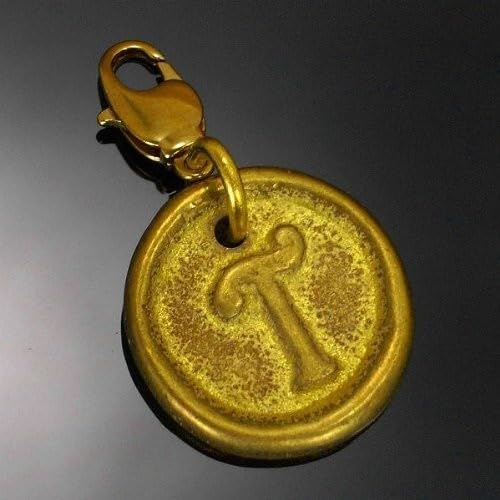 Gold-colored round charm with an ornate letter "T" design.