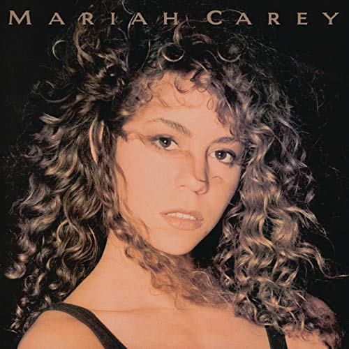 Close-up portrait of Mariah Carey with long curly hair against a black background.