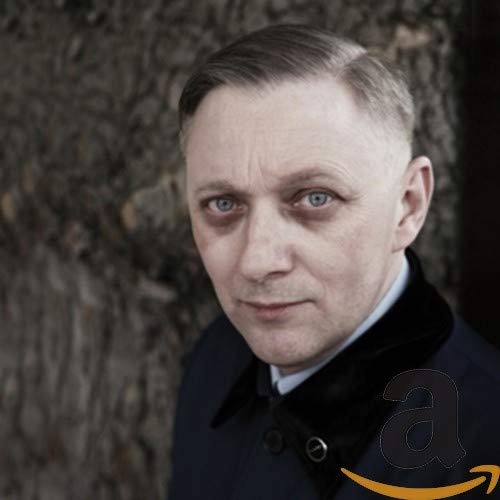 Close-up portrait of Mark Reeder, a man with short hair and blue eyes.