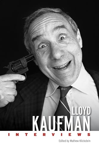 Black and white portrait of Lloyd Kaufman holding a gun to his head.
