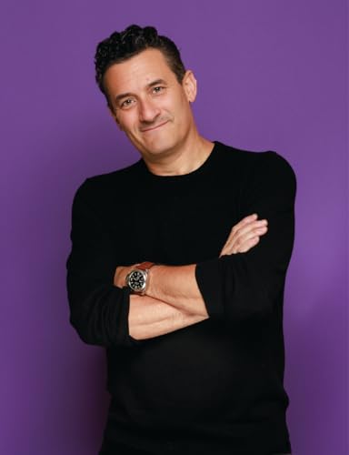 Portrait of a man with crossed arms against a purple background.
