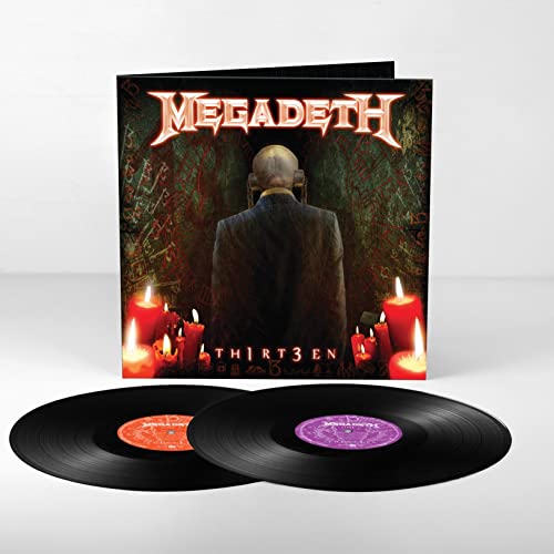 A figure in a suit stands before a dark wall with candles in the foreground.