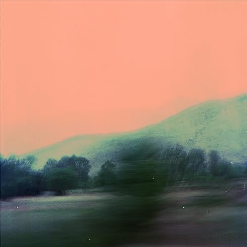 Blurred landscape with green hills against a pink-orange sky.