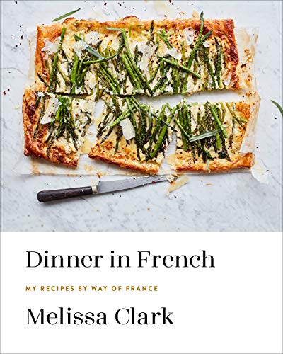 A cookbook cover featuring a sliced asparagus tart on a white marble surface.