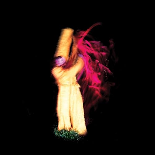 A blurry, motion-filled figure in beige clothing stands against a black background.