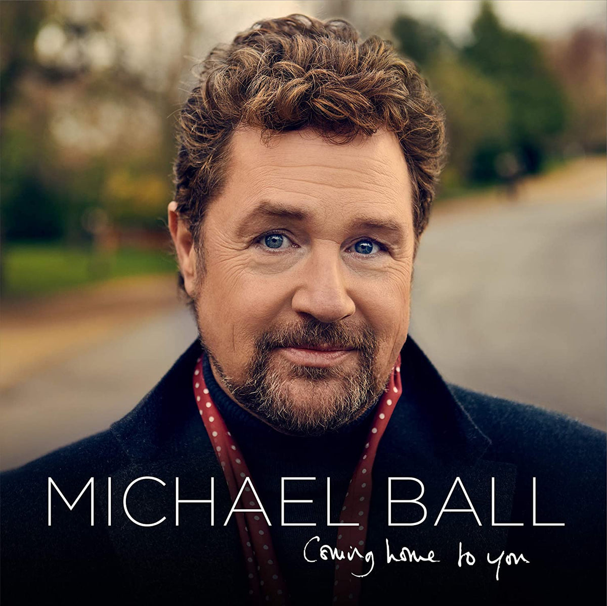 "Album cover featuring a man with curly hair and beard, outdoors."