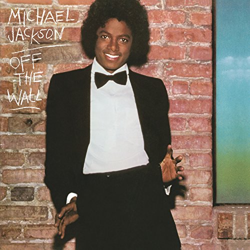 Michael Jackson in a tuxedo leaning against a brick wall.
