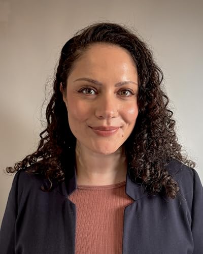 Portrait of a woman with curly dark hair, wearing a dark blazer.