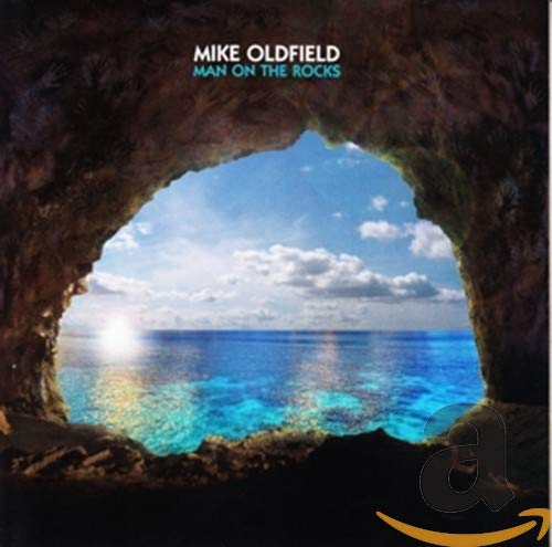 Photo of a rock archway overlooking a body of water with a blue sky.