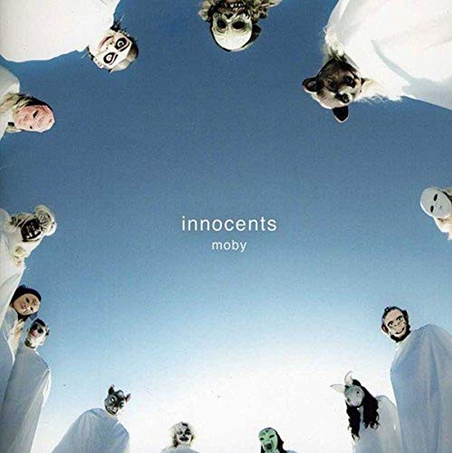 People in white robes and animal masks looking down against a blue sky.