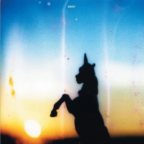 Silhouetted unicorn against a blurred, colorful sunset sky.