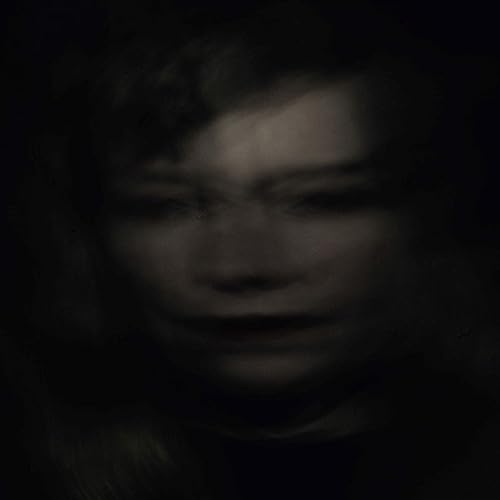 Dark, blurry portrait of a person with indistinct facial features.