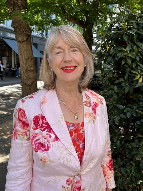 Smiling woman with short blonde hair wearing a floral jacket.