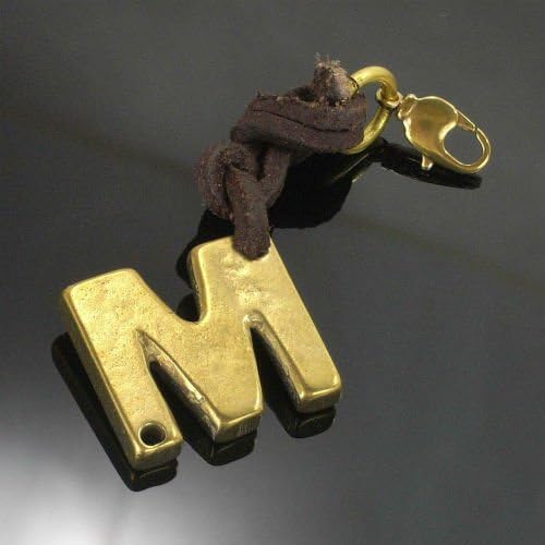 Brass letter "M" charm attached to a dark brown leather cord.