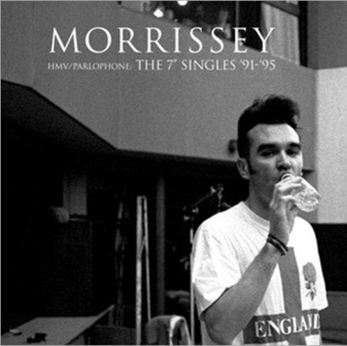 Black and white photo of Morrissey drinking from a water bottle in a studio.