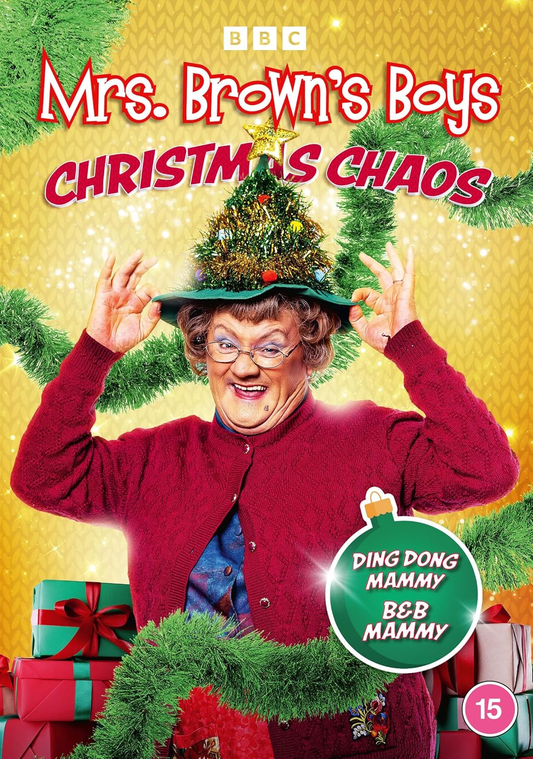 Mrs. Brown wearing a Christmas tree hat on a yellow background with wrapped gifts.