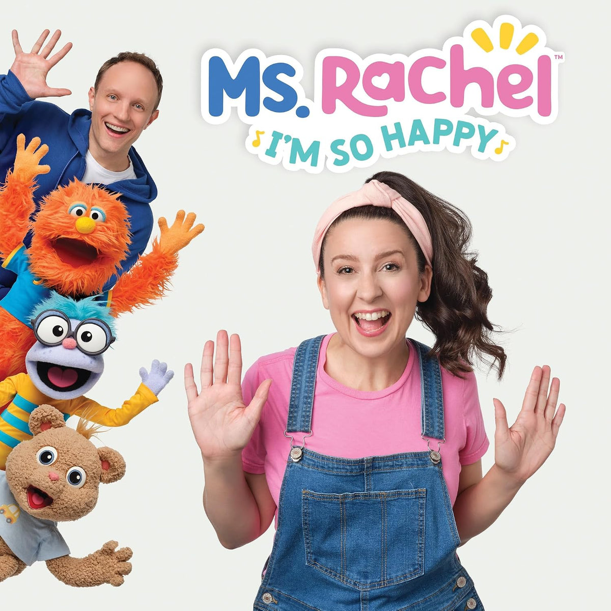 Ms. Rachel with colorful puppets, smiling and waving at the viewer.