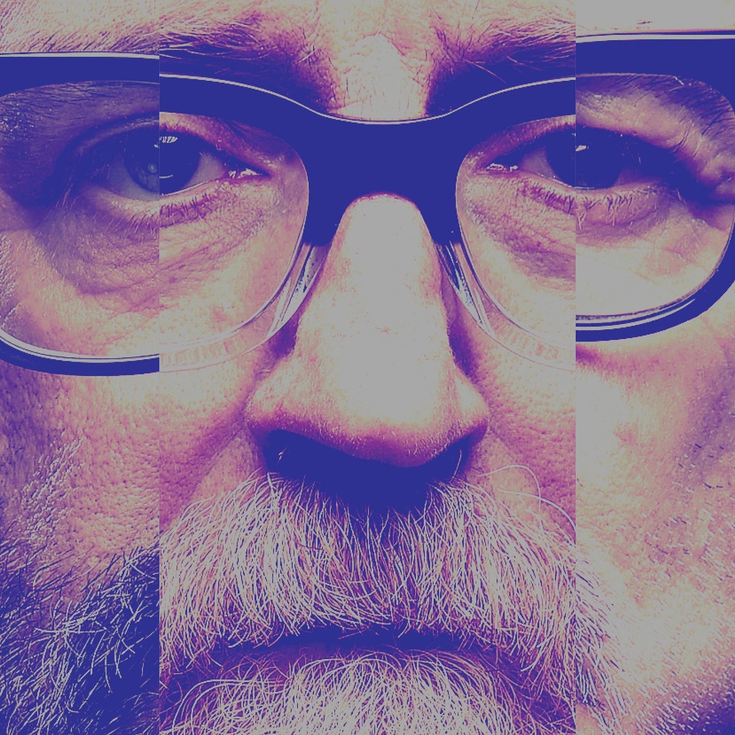 Close-up of a bearded man wearing thick-rimmed glasses, featuring a fragmented, color-tinted photographic effect.