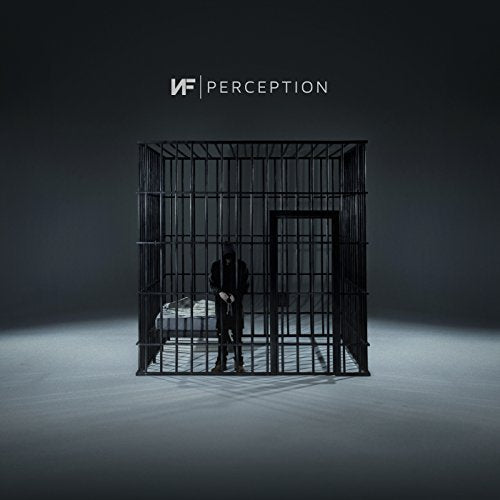 A person in a hoodie stands inside a metal cage on a grey background.
