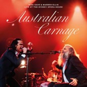 Nick Cave and Warren Ellis performing live on a red stage.