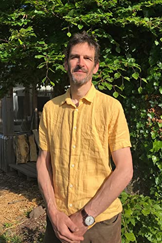 Man with short brown hair wearing a yellow shirt outdoors.