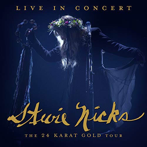 Stevie Nicks in concert, wearing a floral crown and holding a microphone.