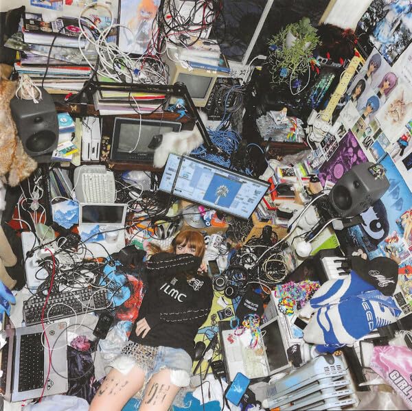 A person lies on a floor cluttered with computer equipment, wires, and electronic debris.