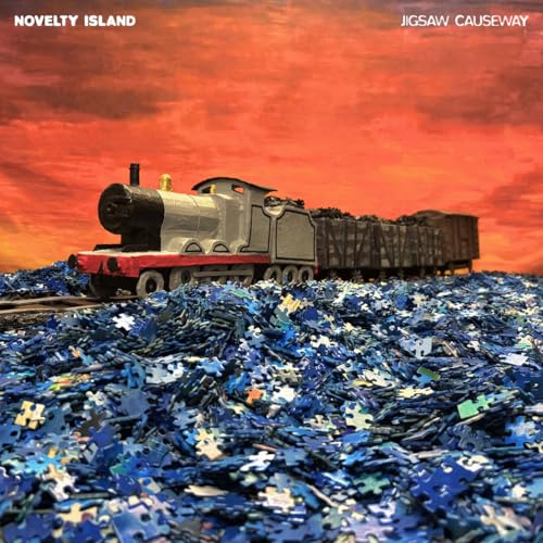 Toy train on a track made of blue jigsaw puzzle pieces.