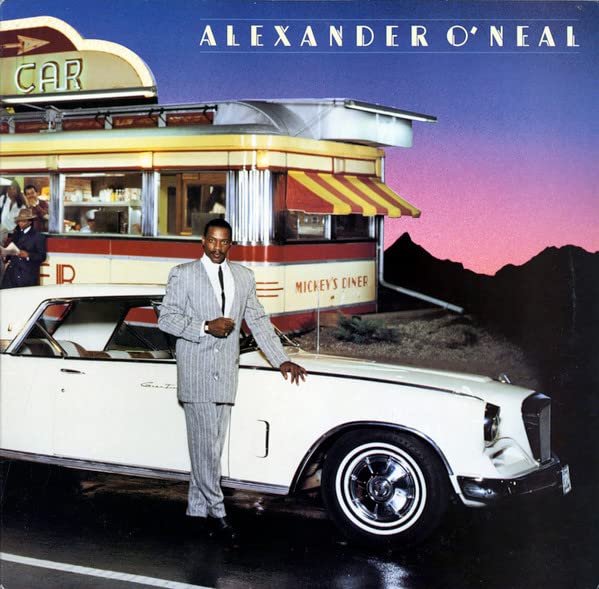 Alexander O’Neal poses with a classic car and diner backdrop.