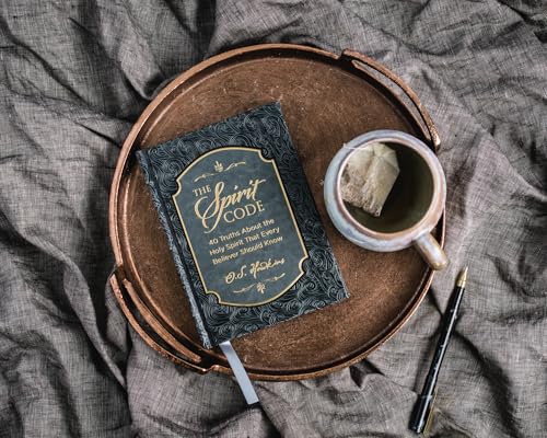 Book, “The Spirit Code,” with a teacup on a textured, round tray.