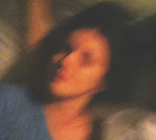 Blurred, orange-toned portrait of a person with obscured features.
