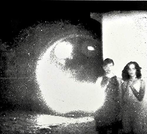 Black and white photo of three people in front of a bright shape.