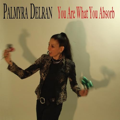 Palmyra Delran album cover: woman in jacket holding objects, casting shadows.