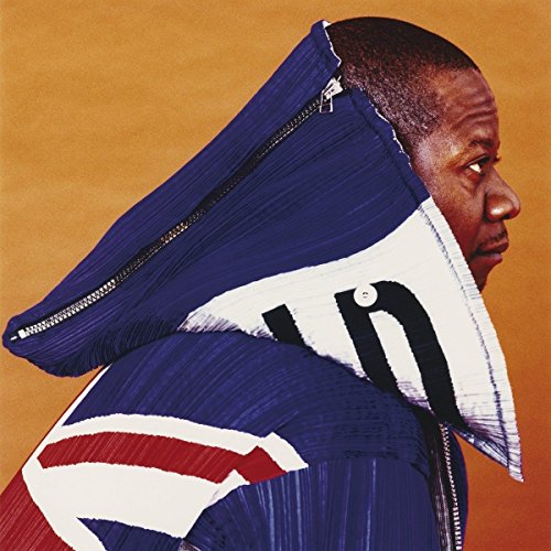 Papa Wemba in profile wearing a striking blue and white pleated jacket.