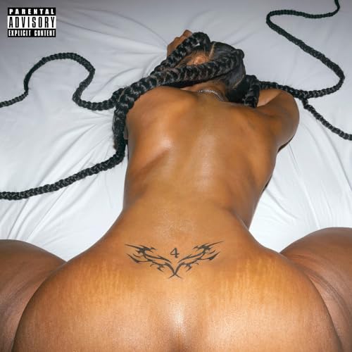A person with long braided hair lying on white sheets with a lower back tattoo.