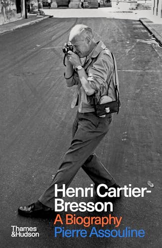Black and white photo of Henri Cartier-Bresson taking a picture on a city street.